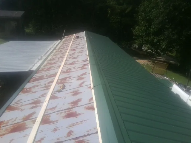 Old rusted panels beside newly installed green metal roofing — Wind Damage Roof Repair by Roofing Brothers in Ebensburg