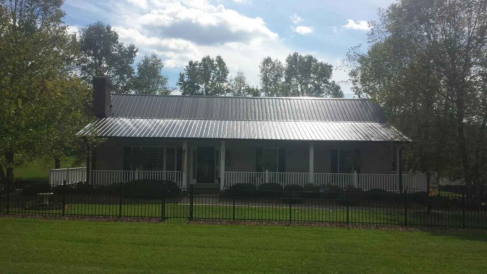 Gray metal roof on a brick ranch with a full width front porch — Gutter Guard Installation work by our crew in Ebensburg