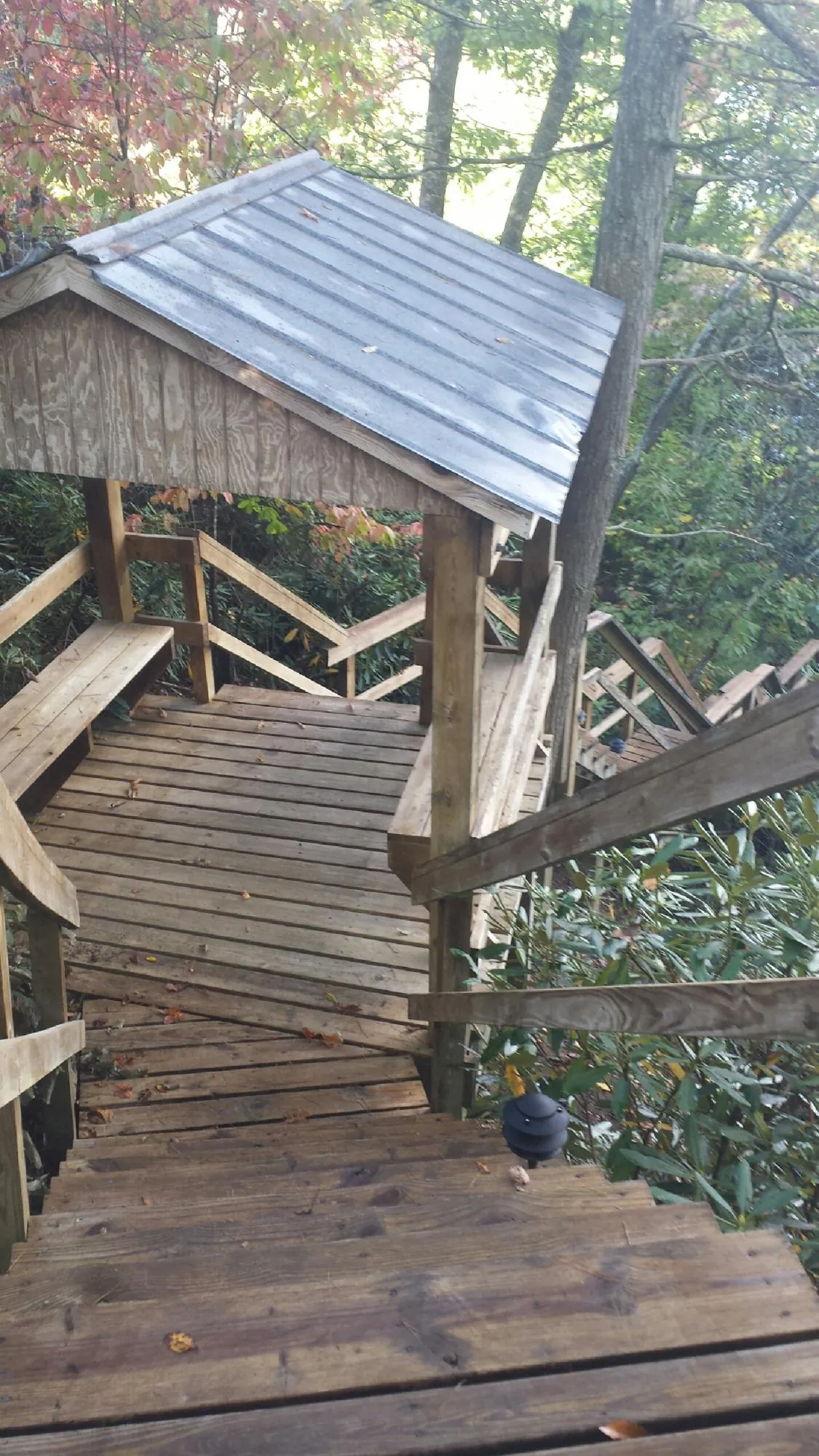 Metal roofed shelter over wooden steps on a wooded walkway — Skylight Repair & Installation work by our crew in Ebensburg