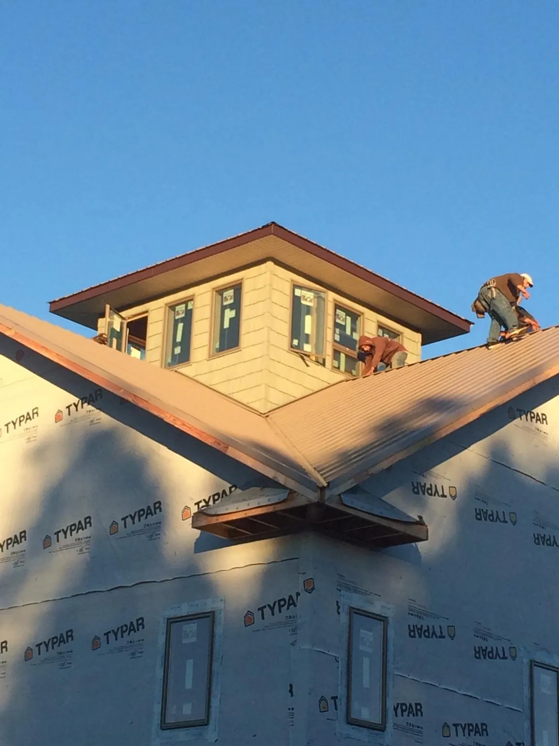 Roofers working around a rooftop cupola on a new metal roof at sunset — Roof Waterproofing in Ebensburg by Roofing Brothers